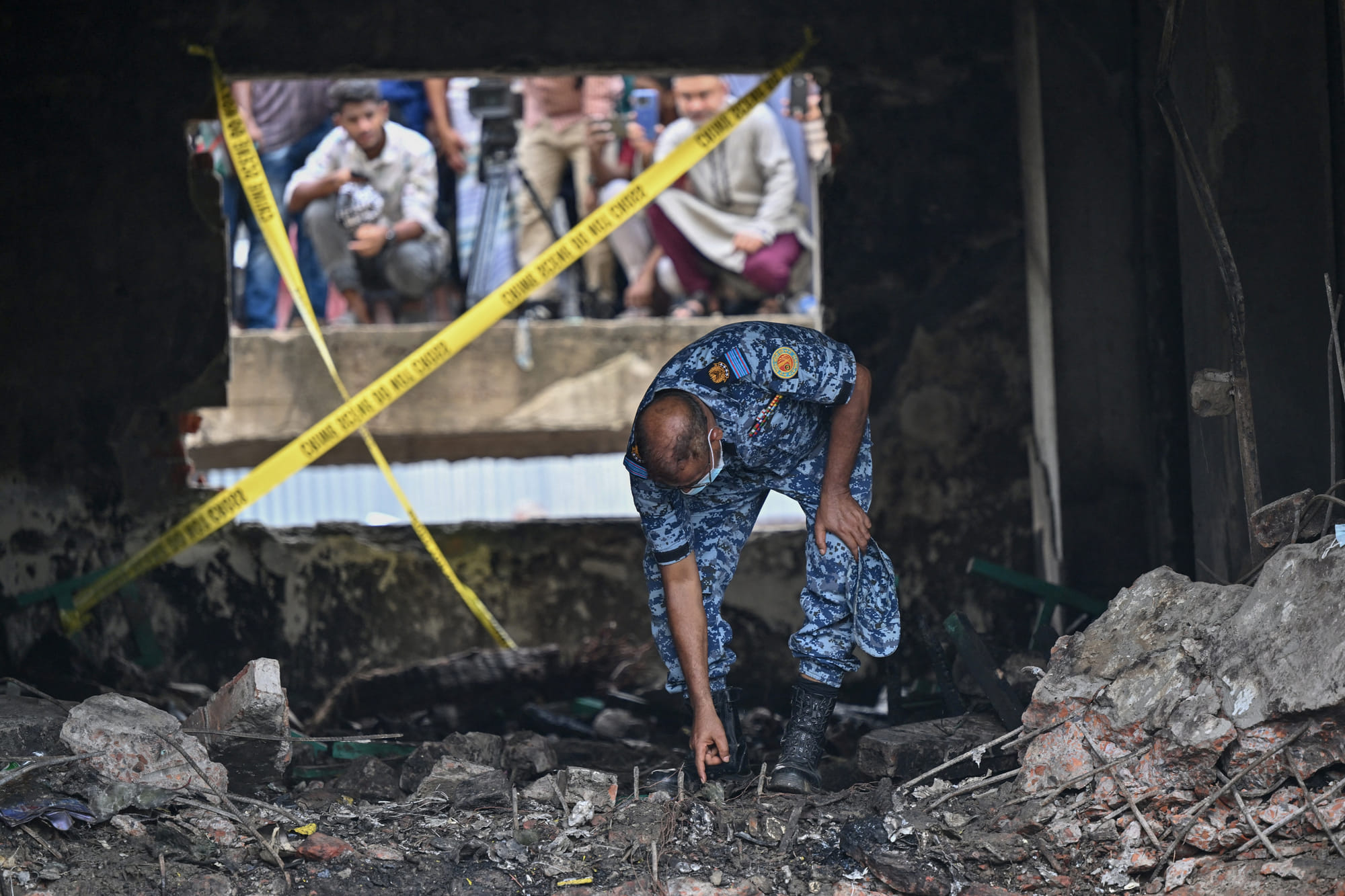 A Bangladesh Air Force personnel inspects the crash site a day after a training jet crashed into a school in Dhaka on July 22, 2025.