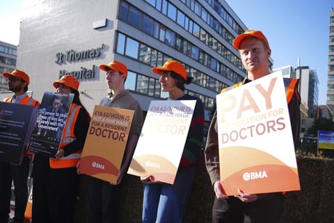 NHS resident doctors hold placards outside St Thomas' Hospital in London, as resident doctors in England, formerly referred to as junior doctors, begin a five-day strike after talks with the government collapsed over pay, Friday, July 25, 2025.