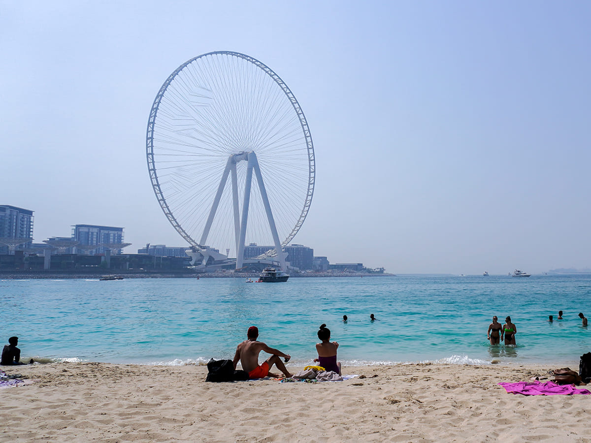 People sunbathe along the Marina beach near the Ain Dubai Ferris wheel.