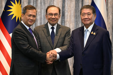 Malaysia's Prime Minister Anwar Ibrahim (C), Cambodia's Prime Minister Hun Manet (L) and Thailand's acting Prime Minister Phumtham Wechayachai (R) pose for photos as they shake hands following a press conference after talks on a possible ceasefire between Thailand and Cambodia in Putrajaya on July 28, 2025.
