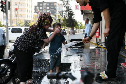 A woman puts water of the face of her child during an extreme heatwave at Silopi district in Sirnak on July 30, 2025.