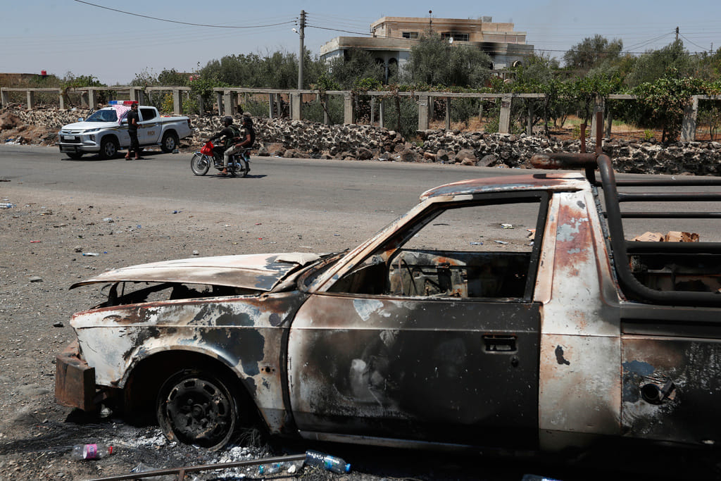 A Syrian security checkpoint is seen as forces deploy in Mazraa village on the outskirts of Sweida city, in southern Syria, Sunday, July 20, 2025. A burned-out vehicle is seen in the foreground.