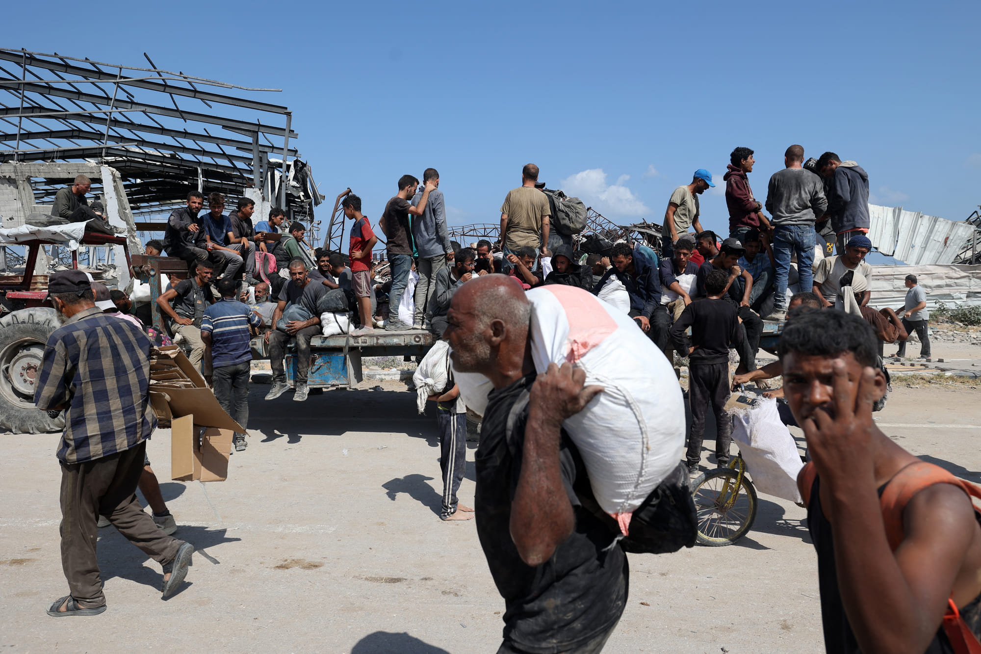 Palestinians transport bags as they return from a food distribution point run by the US and Israeli-backed Gaza Humanitarian Foundation (GHF) group, near the Netsarim corridor in the central Gaza Strip on August 3, 2025.