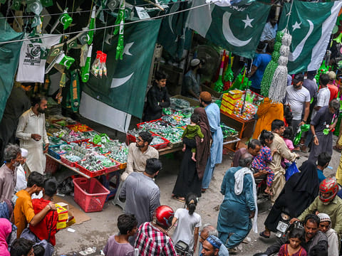 People crowd a marketplace with shops selling Pakistan's national flags and other items ahead of the country's Independence Day celebrations in Lahore on August 10, 2025. 