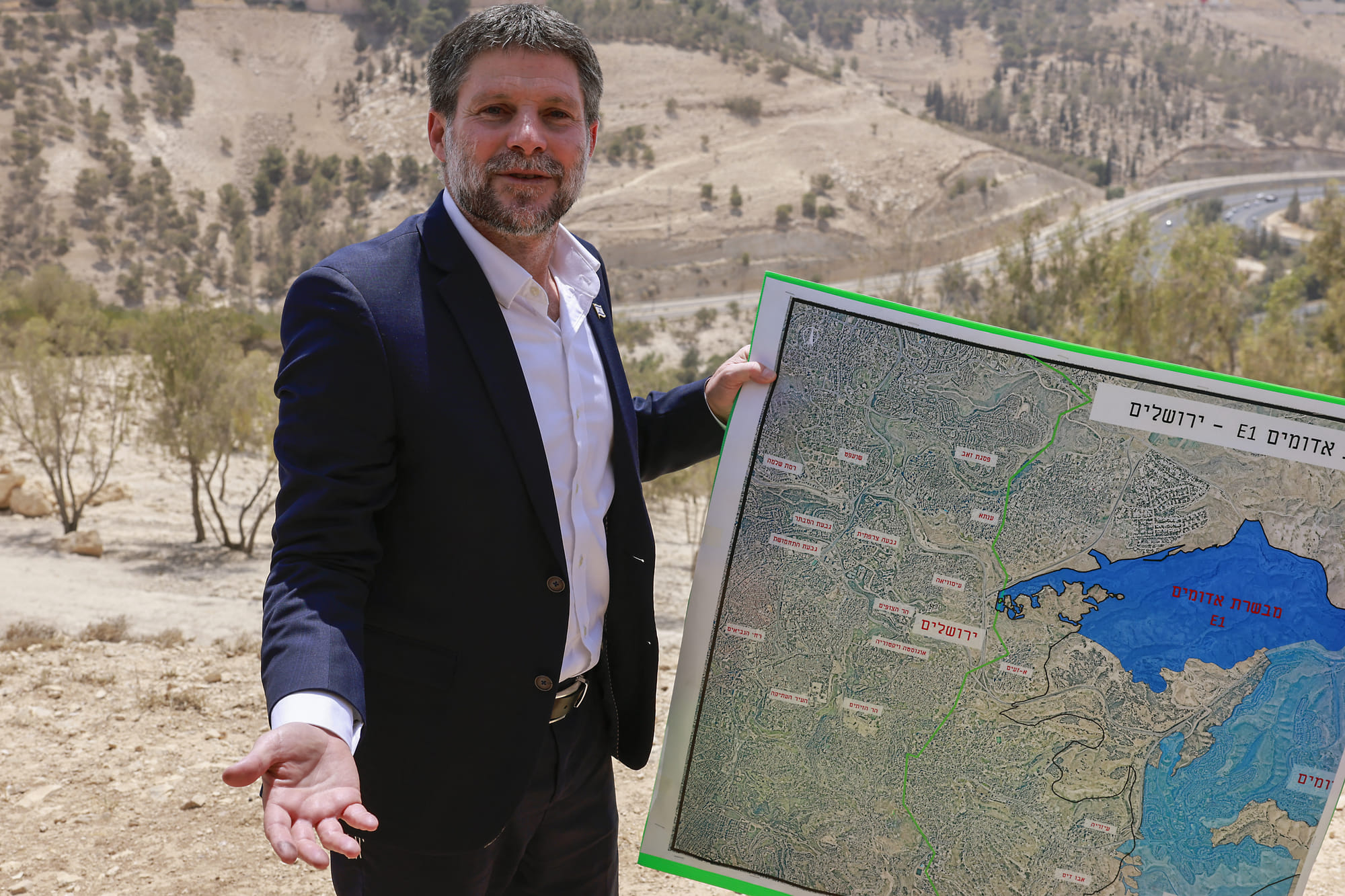 Israeli far-right Finance Minister Bezalel Smotrich holds a map of an area near the settlement of Maale Adumim, a land corridor known as E1, outside Jerusalem in the occupied West Bank, on August 14, 2025, after a press conference at the site.