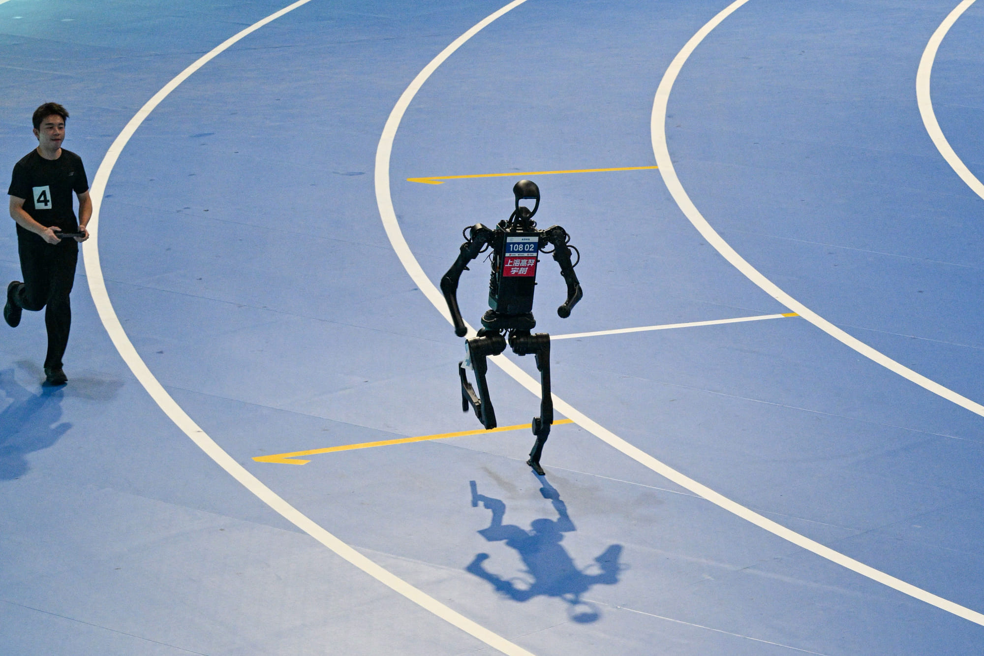 An engineer (L) controls a robot as it competes in the 400M run during the World Humanoid Robot Games in Beijing on Friday.