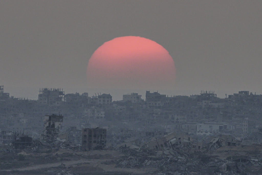 The sun sets behind buildings destroyed during Israeli ground and air operations in the Gaza Strip, as seen from southern Israel, Tuesday, August 26, 2025. 