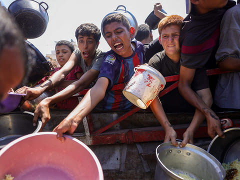 People try to get rice from a charity kitchen providing food for free in the west of Gaza City, on August 28, 2025, as the war between Israel and the Hamas militants movement continues. 