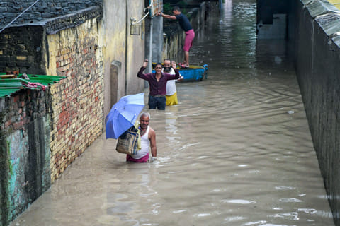 People walk through a waterlogged area as the river Yamuna crosses the danger mark following incessant rainfall, at Yamuna Bazar in New Delhi on Tuesday.  