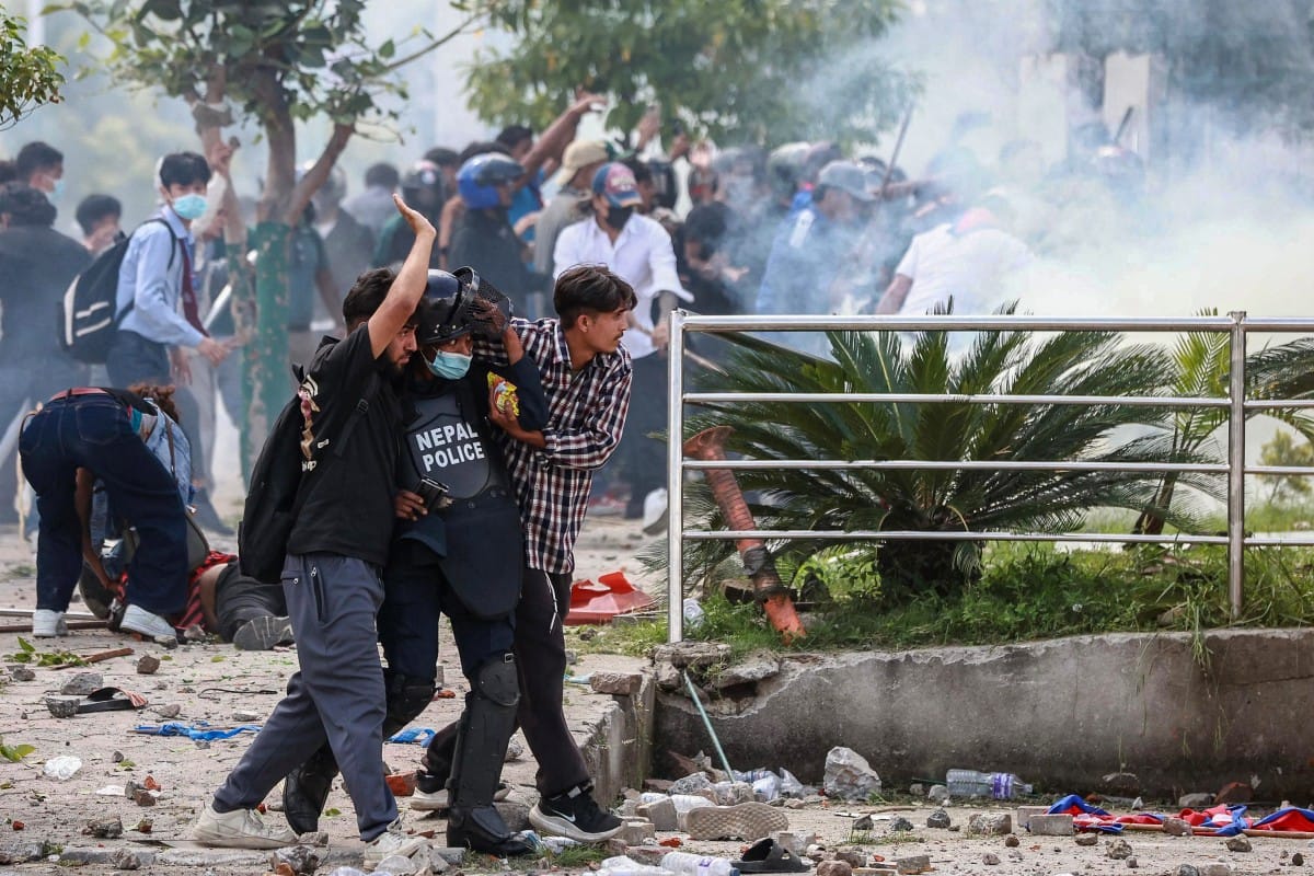 Demonstrators carry an injured police personnel during a protest outside the Parliament in Kathmandu on September 8, 2025, held to condemn the government over social media prohibitions and corruption.