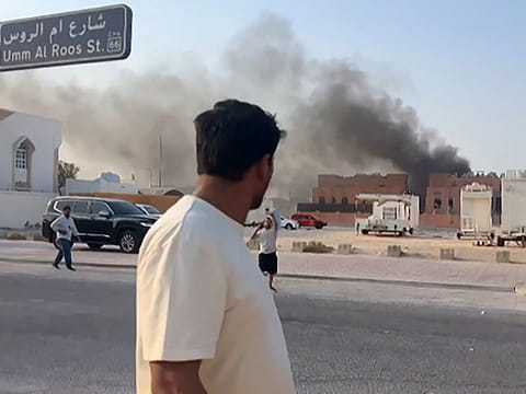 A man looking at smoke billowing after explosions in Doha's capital Qatar.