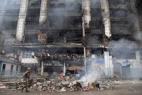 An Army personnel patrols along a street as smoke billows from a burning supermarket building of Nepal's renowned retail chain Bhat-Bhateni, a day after it was set ablaze by protesters in Kathmandu on September 10, 2025.