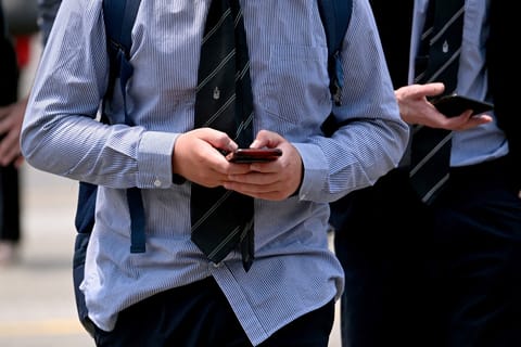 A file photo taken on November 28, 2024 shows young people looking at their phones in Melbourne as Australia looks to ban children under 16 from social media.