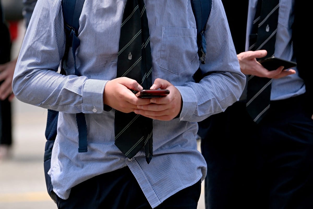 A file photo taken on November 28, 2024 shows young people looking at their phones in Melbourne as Australia looks to ban children under 16 from social media.