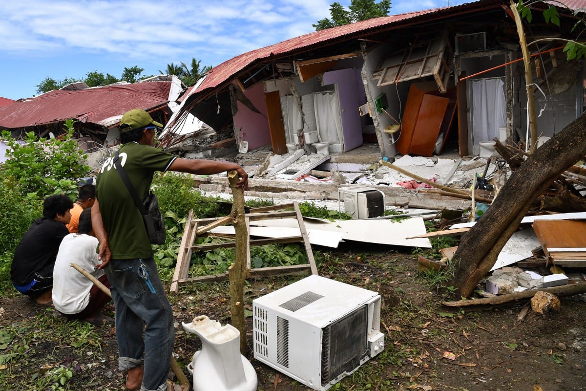 People inspect a collapsed building where three people were reported missing in Bogo City.
