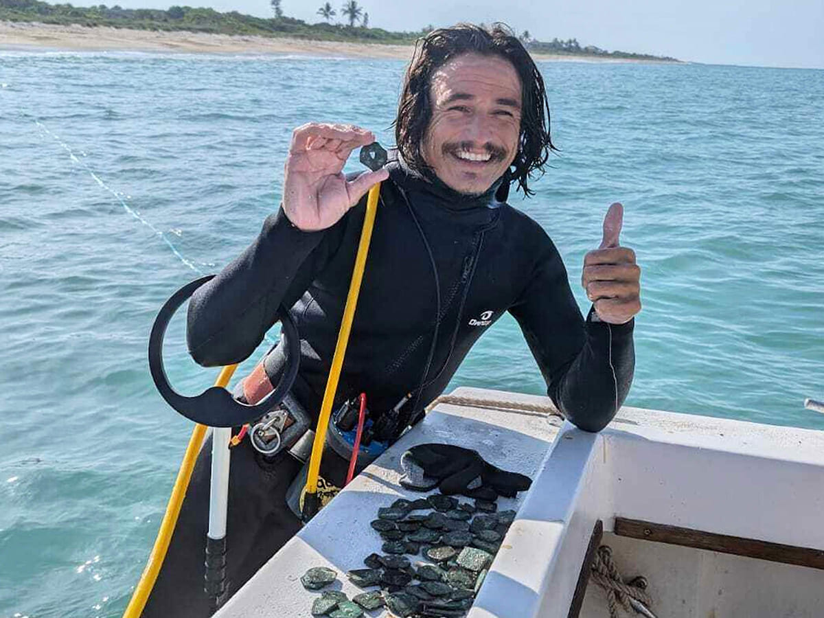 Diver Levin Shavers shows coins uncovered from a Spanish shipwreck off the Atlantic coast of Florida.
