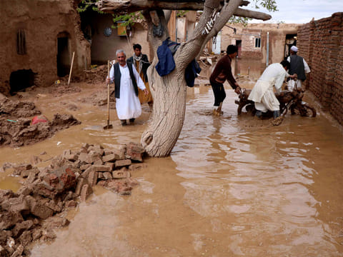 Residents clear debris and wade through floodwater after heavy rains and flash floods hit parts of Afghanistan. 