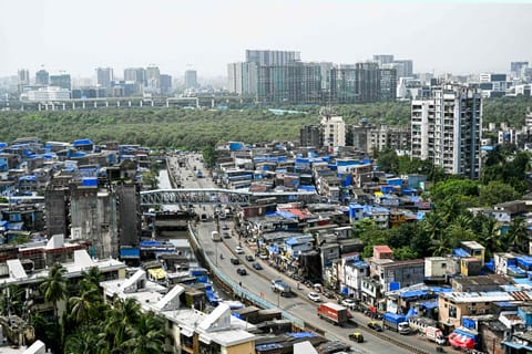 High-rise buildings tower over the densely packed homes of Dharavi, Mumbai’s sprawling slum settlement, in this photograph taken on July 12, 2025. A massive $8 billion redevelopment project, led by the Mumbai authorities and Adani Realty, aims to transform Asia’s largest slum into a modern urban district.