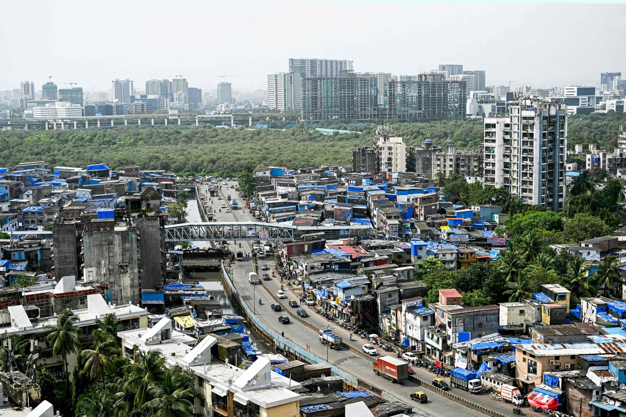 High-rise buildings tower over the densely packed homes of Dharavi, Mumbai’s sprawling slum settlement, in this photograph taken on July 12, 2025. A massive $8 billion redevelopment project, led by the Mumbai authorities and Adani Realty, aims to transform Asia’s largest slum into a modern urban district.