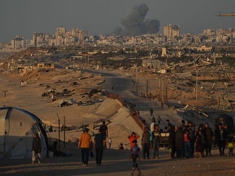 Displaced Palestinians walk along the coastal road, backdropped by smoke rising into the sky in Gaza City on Wednesday October 8.