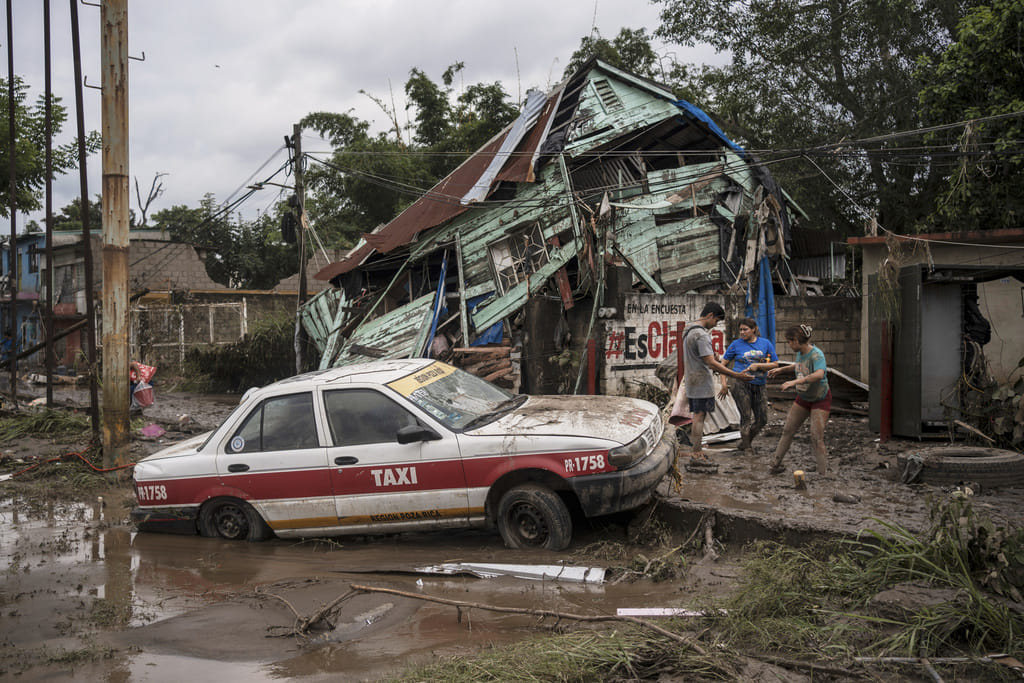 Neighbours gather around a damaged house after heavy rainfall in Poza Rica, Veracruz state, Mexico, Saturday, Oct. 11, 2025. (AP Photo/Felix Marquez)
