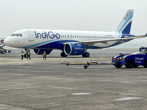 Ground staff walk past an Indigo airlines aircraft taxiing in the apron at the Netaji Subhash Chandra Bose International airport in Kolkata. 