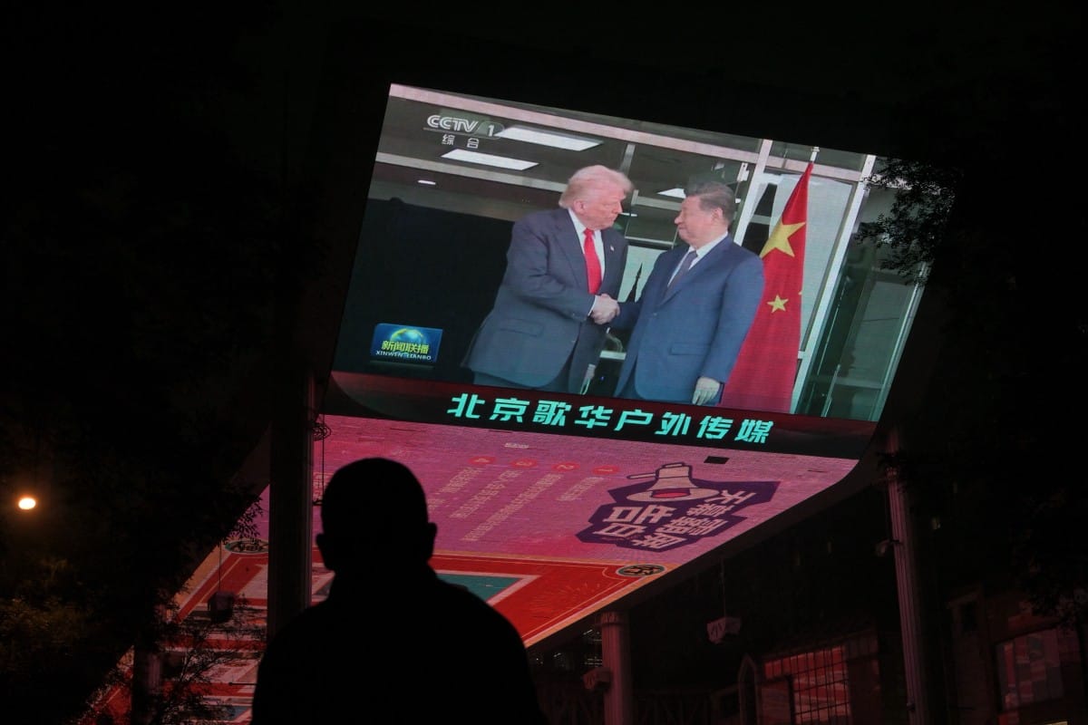 A screen shows news coverage of the meeting between US President Donald Trump and China's President Xi Jinping in South Korea, outside a shopping mall in Beijing on October 30, 2025.