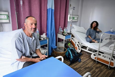 Avalanche survivors France's Didler Armand (L) and Isabelle Thaon sit inside a ward at the Era Hospital in Kathmandu on November 4, 2025.