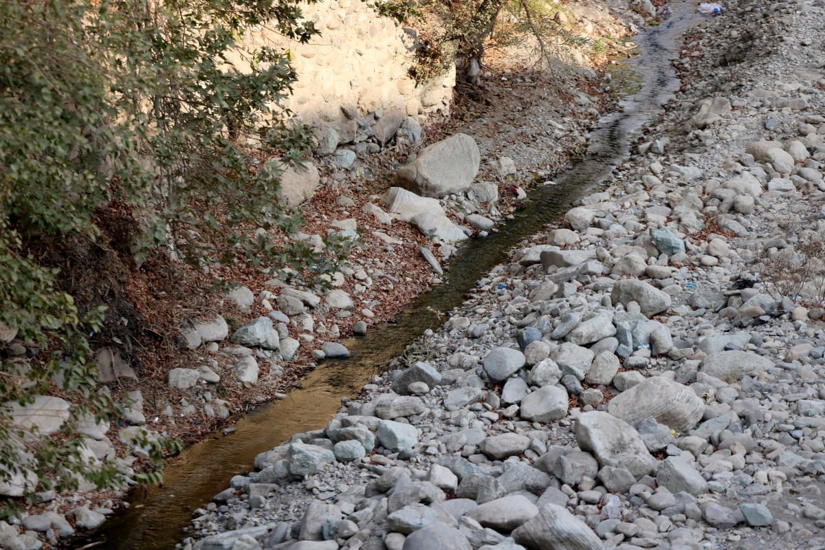 A trickle of water flows in the mainly dried-up Kan River, west of Tehran on November 9, 2025, as the Iran faces sever water shortages.