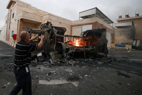 A Palestinian man uses a mobile phone to record a burning truck after an Israeli settlers attack in the village of Beit Lid, east of Tulkarm in the occupied West Bank on November 11, 2025.