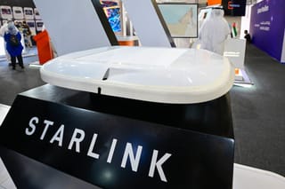A visitor stands near a Starlink antenna for aircraft on display at Al-Maktoum International Airport during the Dubai Airshow 2025 in Dubai on November 20, 2025.