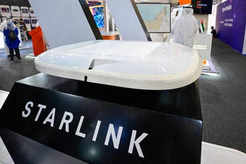 A visitor stands near a Starlink antenna for aircraft on display at Al-Maktoum International Airport during the Dubai Airshow 2025 in Dubai on November 20, 2025.