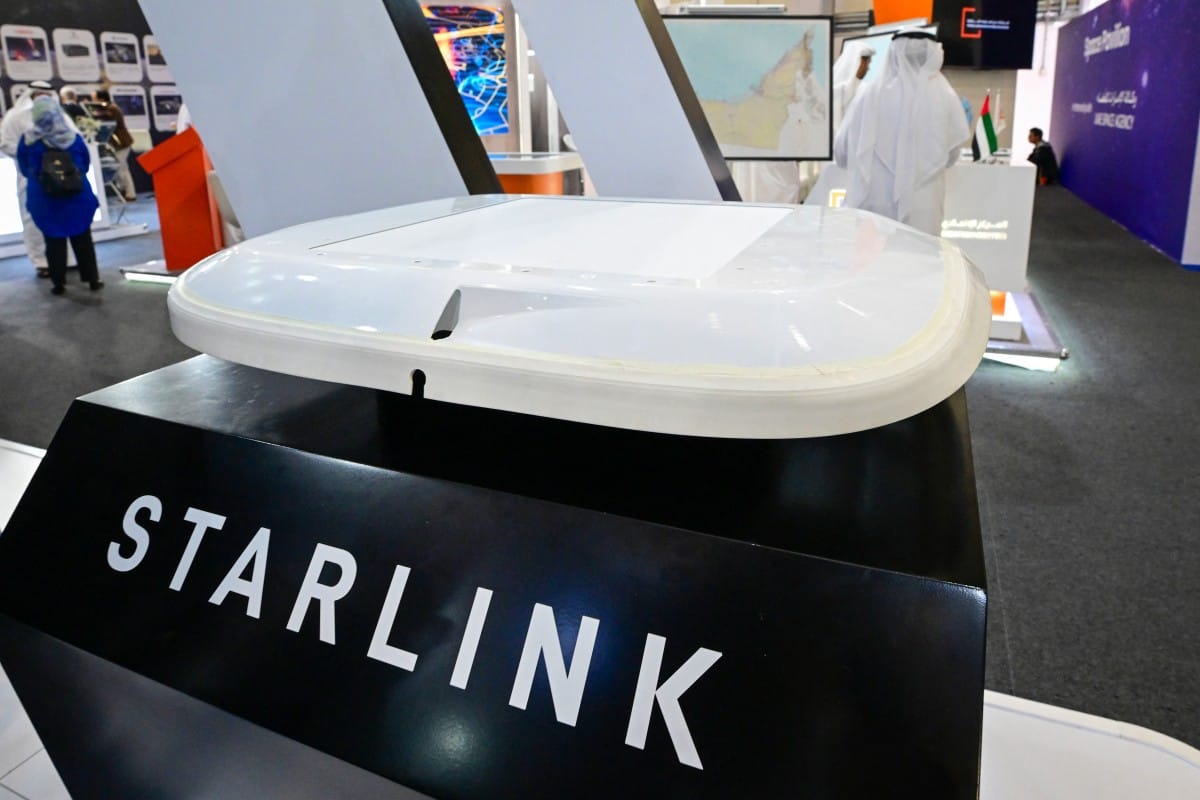 A visitor stands near a Starlink antenna for aircraft on display at Al-Maktoum International Airport during the Dubai Airshow 2025 in Dubai on November 20, 2025.