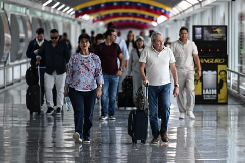 Passengers walk after arriving at Maiquetia Simon Bolivar International Airport in Caracas on November 24, 2025.