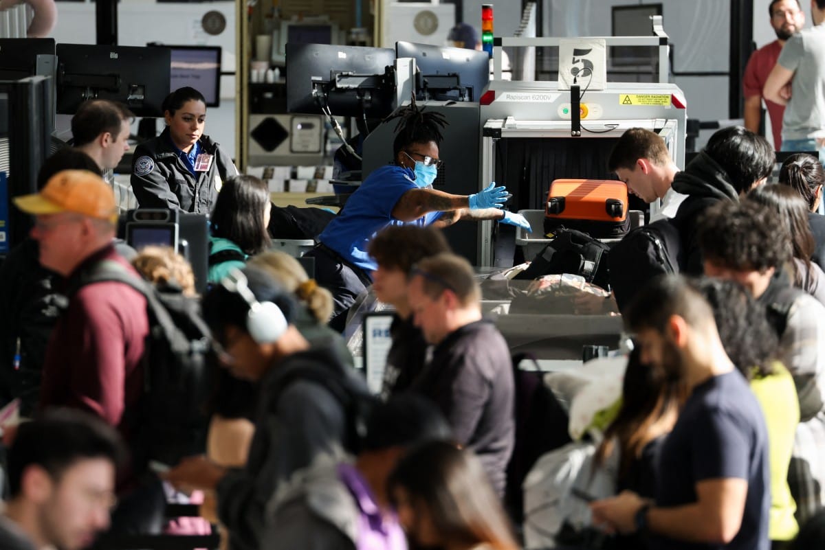Passengers wait in line for a security checkpoint while traveling on November 26, 2025.