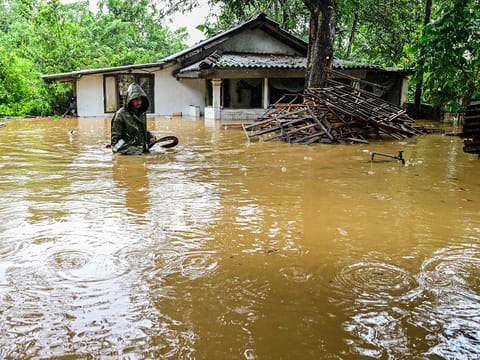 A man wades through floodwaters outside his house after heavy rainfall in Kaduwela on the outskirts of Colombo on November 28, 2025. 