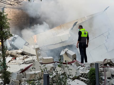 A civil defence member stands on rubble at a damaged site after Israeli military strike in Lebanon.