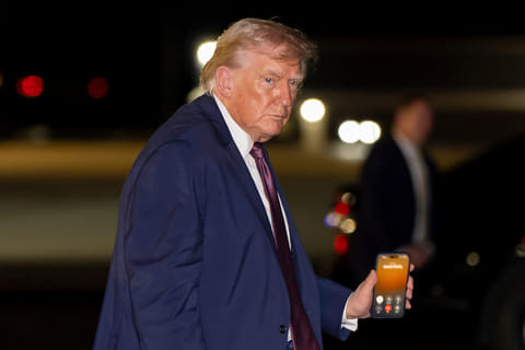 President Donald Trump holds a cell phone with a call to Nvidia CEO Jensen Huang as he departs on Air Force One at Rocky Mount-Wilson Regional Airport, Friday, Dec. 19, 2025, in Elm City, N.C. (AP Photo/Alex Brandon)