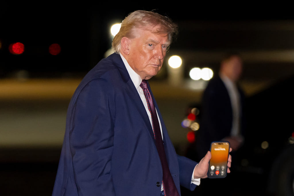 President Donald Trump holds a cell phone with a call to Nvidia CEO Jensen Huang as he departs on Air Force One at Rocky Mount-Wilson Regional Airport, Friday, Dec. 19, 2025, in Elm City, N.C. (AP Photo/Alex Brandon)