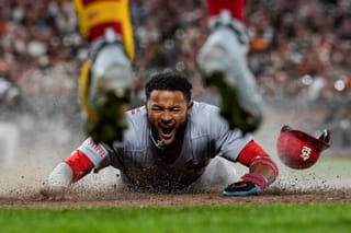 St. Louis Cardinals' Victor Scott II, bottom, scores against the San Francisco Giants on Brendan Donovan's double during the ninth inning of a baseball game, Sept. 23, 2025, in San Francisco.