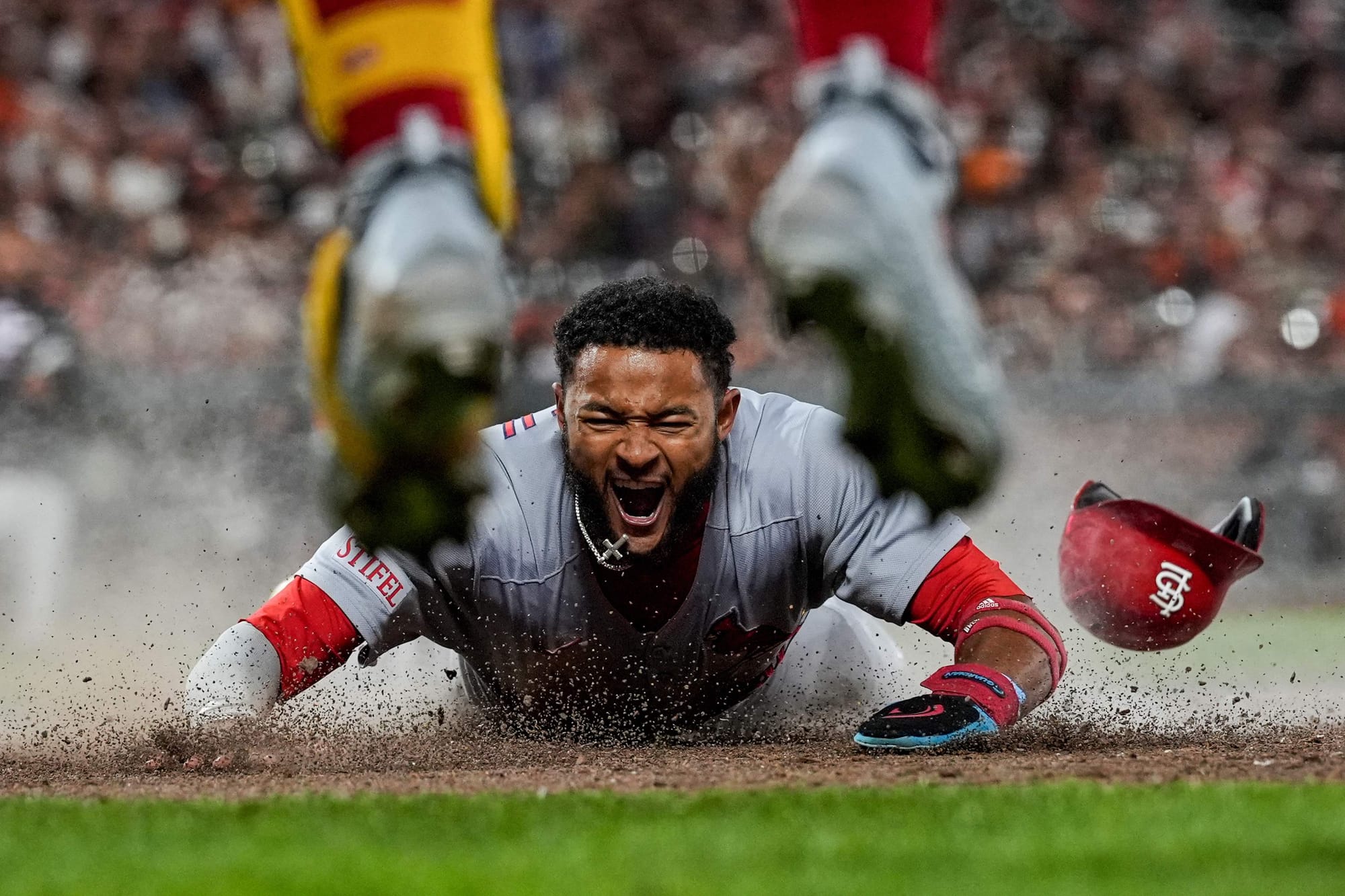 St. Louis Cardinals' Victor Scott II, bottom, scores against the San Francisco Giants on Brendan Donovan's double during the ninth inning of a baseball game, Sept. 23, 2025, in San Francisco.
