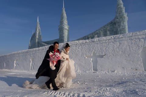 A couple arrives for a mass wedding during the annual Ice and Snow Festival in Harbin, Heilongjiang province, northeastern China, embracing the festive spirit amid snow and ice.