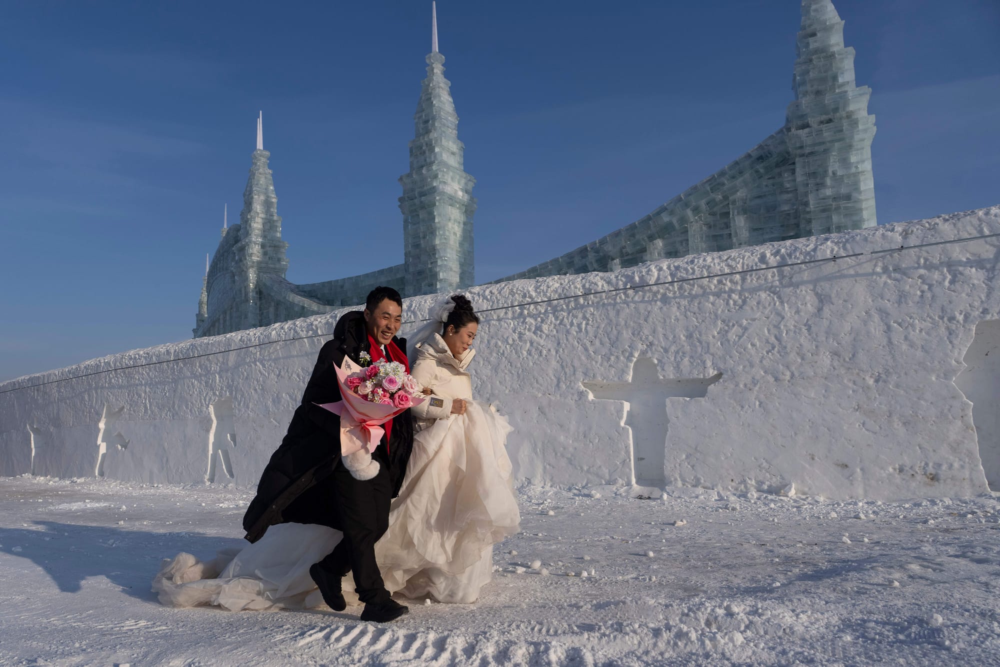 A couple arrives for a mass wedding during the annual Ice and Snow Festival in Harbin, Heilongjiang province, northeastern China, embracing the festive spirit amid snow and ice.