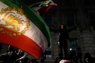 A protestor waves an Iran flag from before the 1979 revolution with the lion and sun emblems during a rally held in Solidarity with Iran's Uprising, organised by The national Council of Resistance of Iran, on Whitehall in central London on January 11, 2026, to protest against the Iranian regime's crackdown on internet access and "recognise their right to self-defence against the regime's forces".