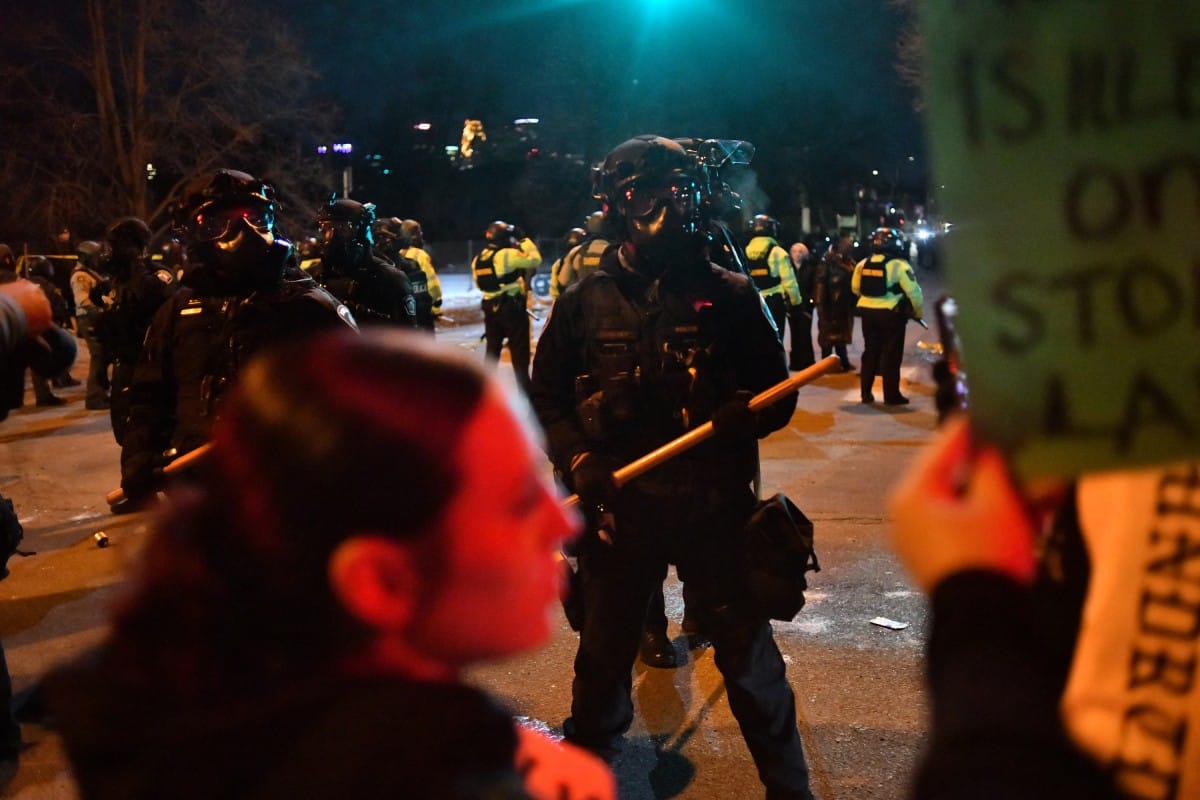 Federal law enforcement agents and police officers in riot gear face off with protesters.