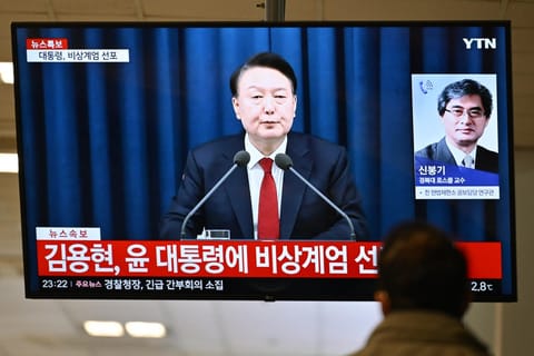 A man watches South Korea's President Yoon Suk Yeol speak during a news broadcast on a television at a train station in Seoul on December 3, 2024, after he declared emergency martial law, saying the step was necessary to protect the country from "communist forces" amid parliamentary wrangling over a budget bill.