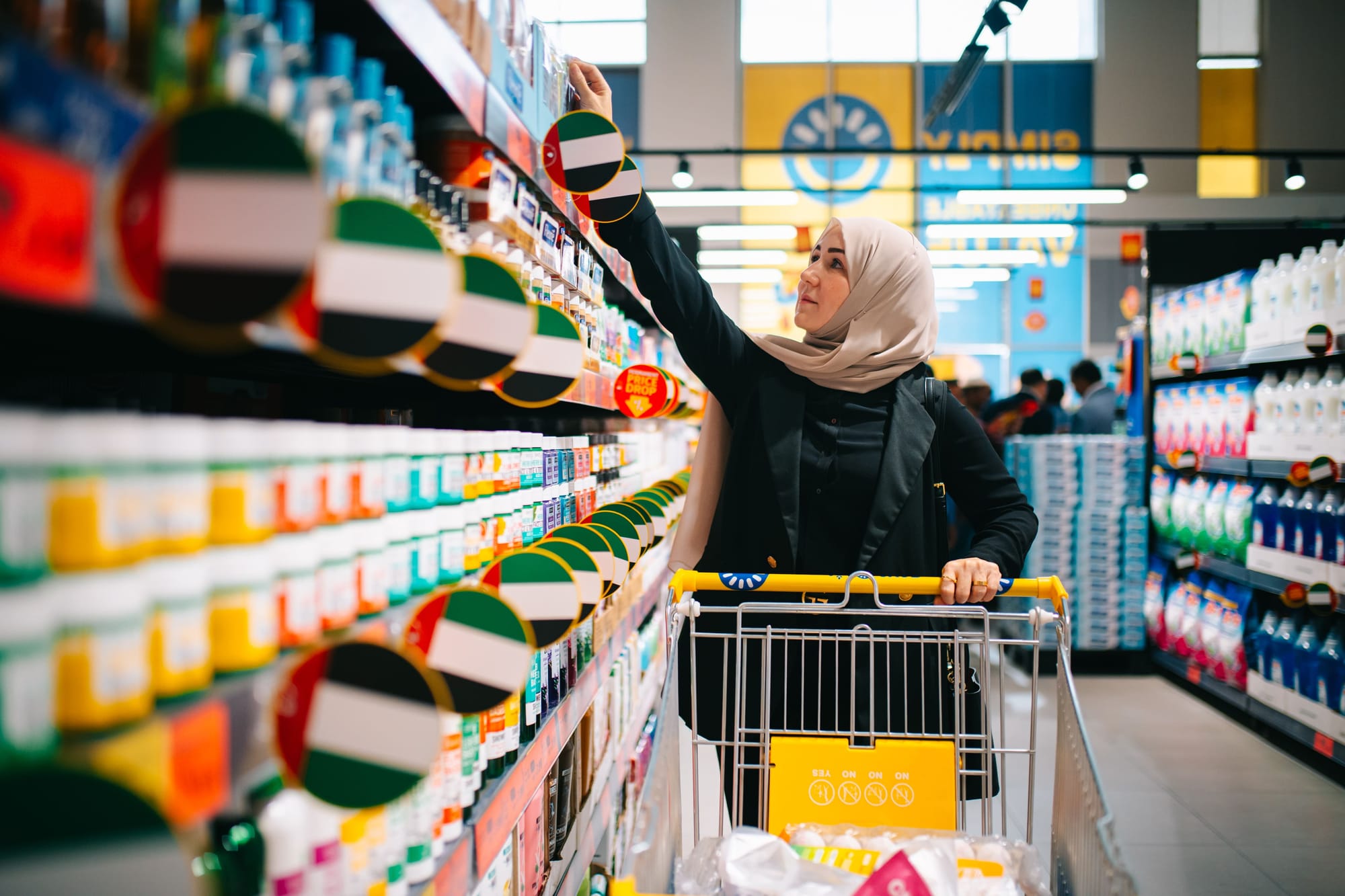 A woman shopping inside a Sava discount store, looking at products on store shelves.