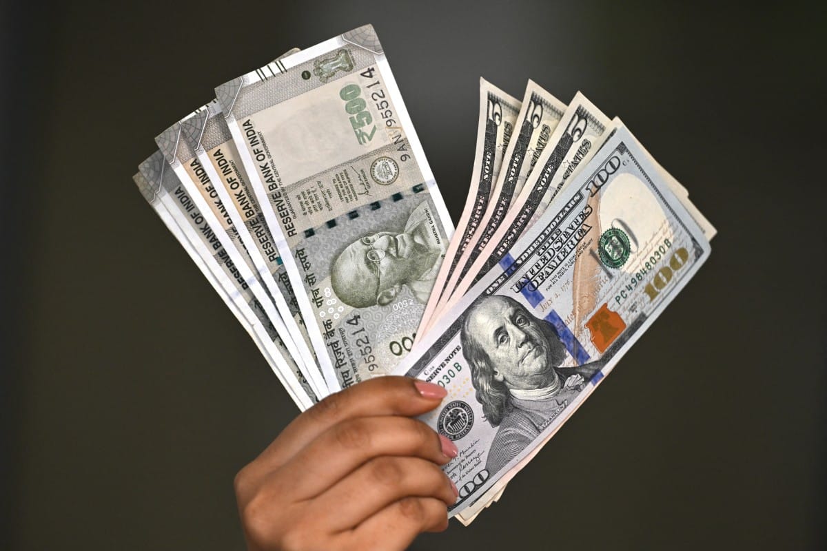 Indian rupee and US dollar currency notes are held by a foreign exchange employee at an office in New Delhi on August 26, 2025.
