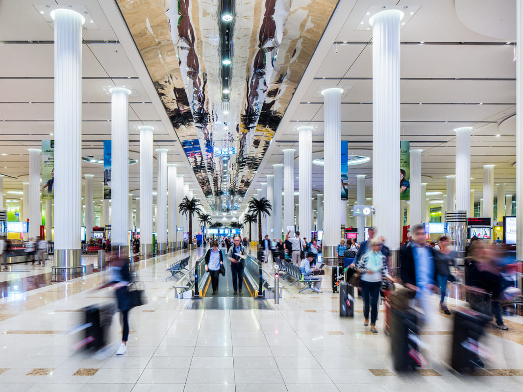 Interior view of Dubai International Airport Terminal 3 with passengers walking through the arrivals area.