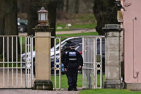 Police officers walk through the gated entrance to Royal Lodge, a 30-room property and former residence to Britain's former prince Andrew where police said they are still conducting a search, in Windsor, west of London on February 20, 2026, a day after Andrew Mountbatten-Windsor was arrested on the royal family's remote Sandringham estate in eastern England.